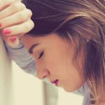 Frustrated woman leaning against a wall with her eyes closed